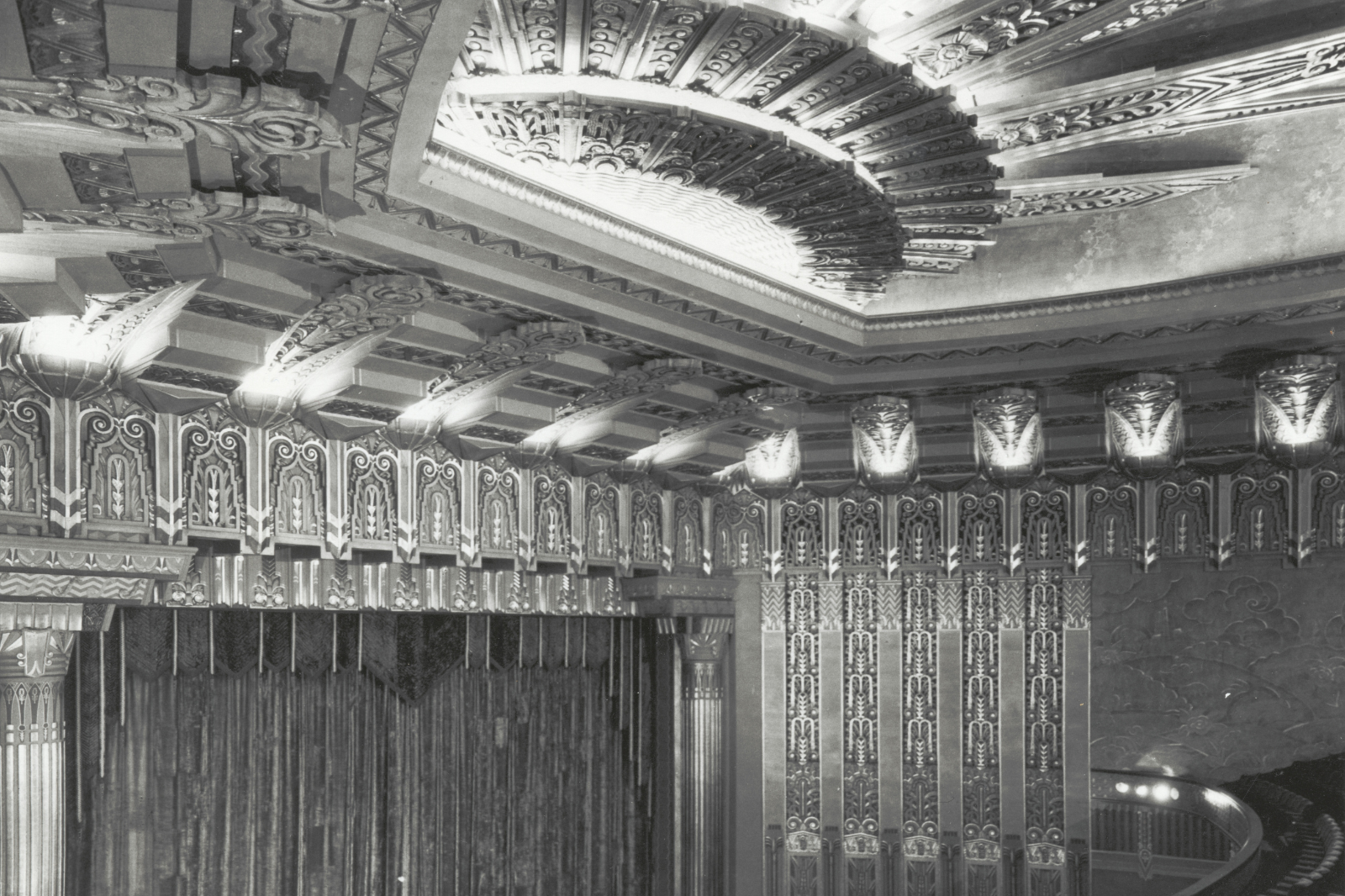 Interior of the Wiltern Theater auditorium, Los Angeles, showing Art Deco design with metallic leaf details, decorative plaster, lighting, and wall mural, ca. 1931.